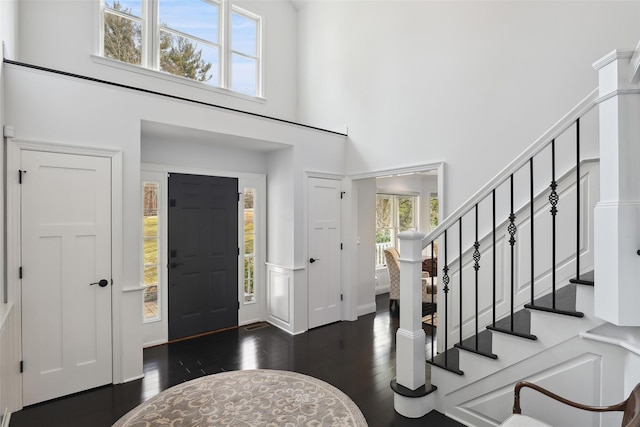 entryway with hardwood / wood-style floors, stairway, and a high ceiling