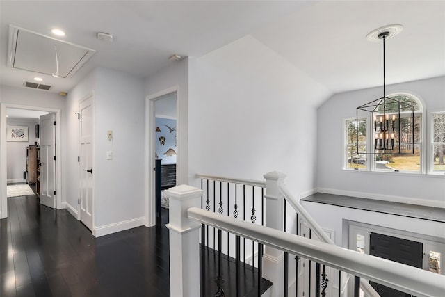 hall featuring visible vents, baseboards, an upstairs landing, dark wood-style floors, and attic access