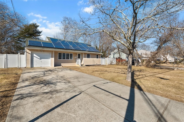 view of front of house with an attached garage, fence, driveway, a gate, and roof mounted solar panels