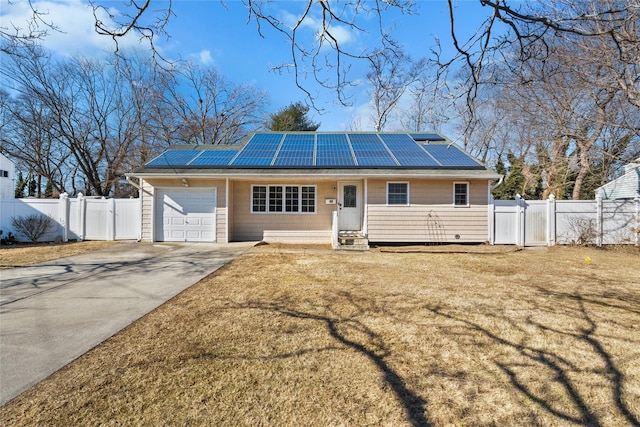 view of front facade with fence, driveway, a gate, roof mounted solar panels, and a front yard