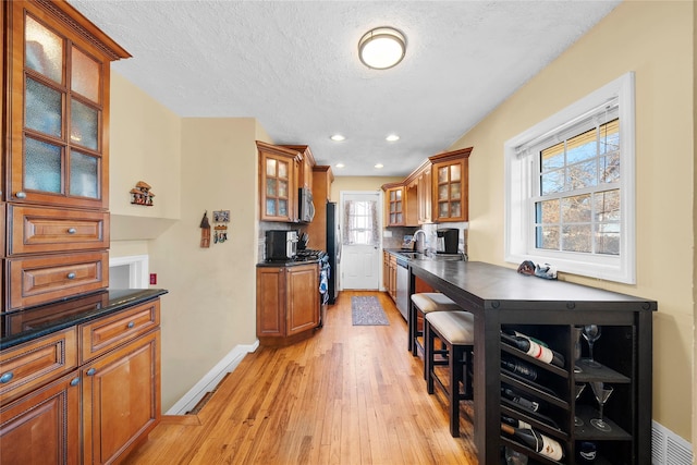 kitchen featuring stainless steel appliances, dark countertops, a sink, and brown cabinets