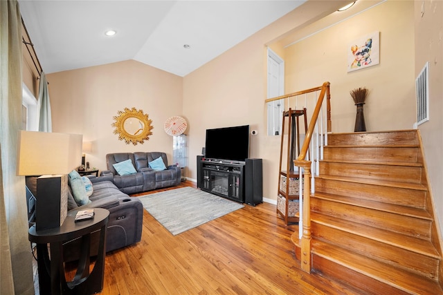 living room with baseboards, visible vents, lofted ceiling, stairs, and light wood-style floors