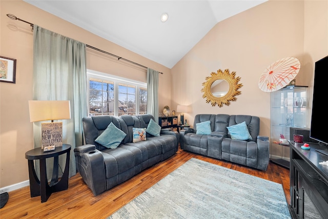 living room featuring high vaulted ceiling, baseboards, and wood finished floors