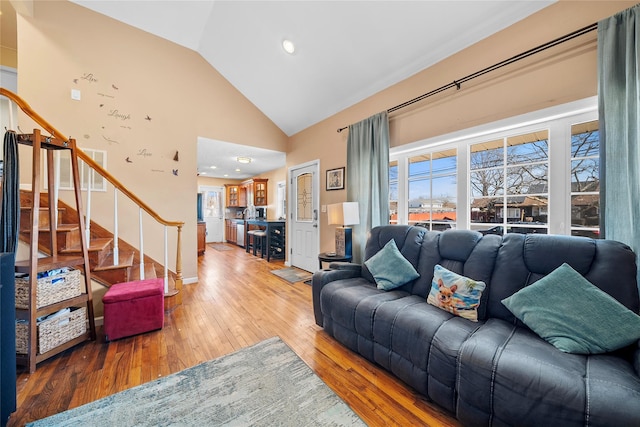 living room with stairs, high vaulted ceiling, and hardwood / wood-style flooring