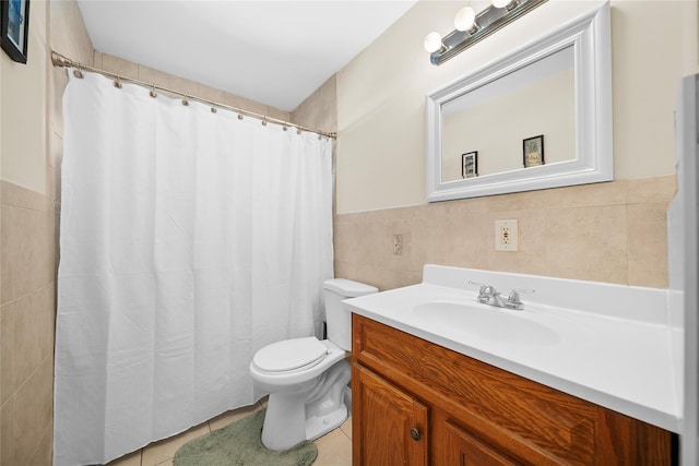 bathroom with toilet, vanity, tile walls, wainscoting, and tile patterned floors