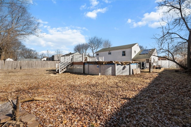 rear view of house featuring a fenced backyard, stairway, a deck, and a fenced in pool