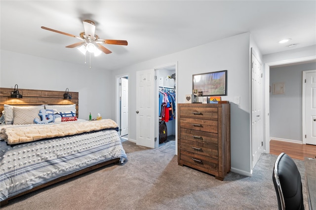 carpeted bedroom featuring a ceiling fan, a closet, a spacious closet, and baseboards