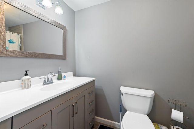 full bath with baseboards, vanity, and toilet