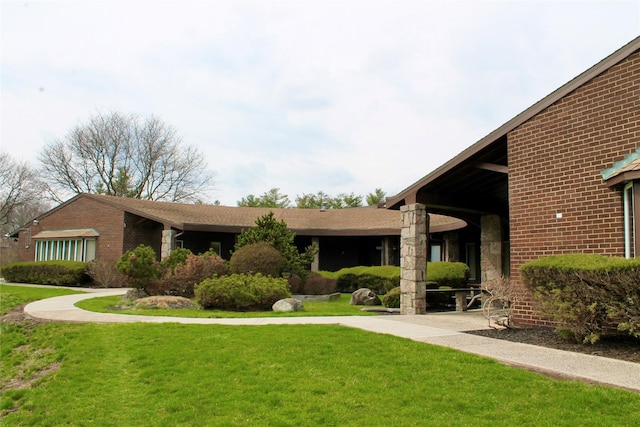 exterior space with brick siding and a front yard