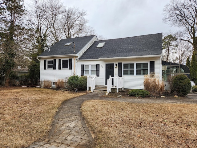 view of front of home with roof with shingles and a front lawn