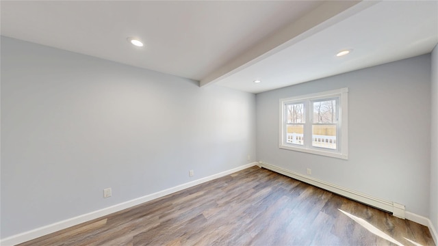 empty room featuring a baseboard heating unit, beamed ceiling, wood finished floors, and baseboards