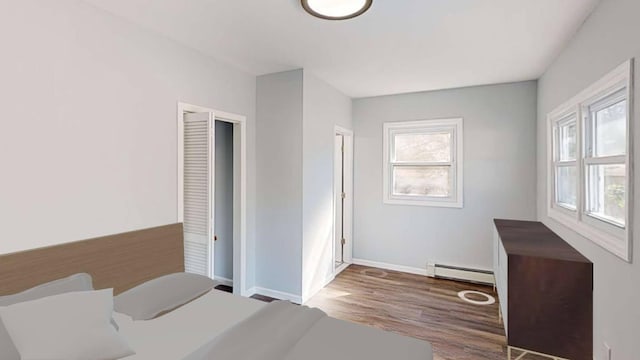 bedroom featuring a baseboard radiator, wood finished floors, and baseboards