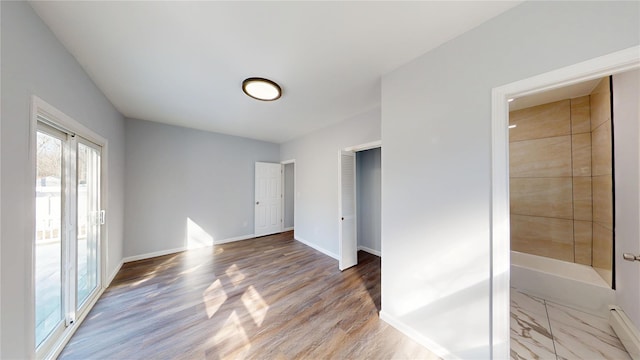 unfurnished bedroom featuring access to outside, baseboards, and wood finished floors