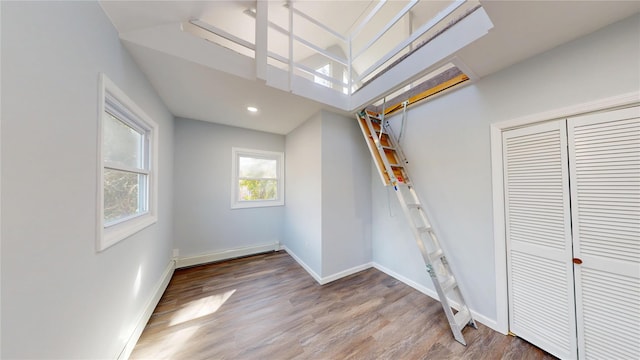 below grade area with recessed lighting, a baseboard radiator, wood finished floors, and baseboards