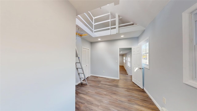 unfurnished room featuring recessed lighting, a high ceiling, baseboards, and wood finished floors