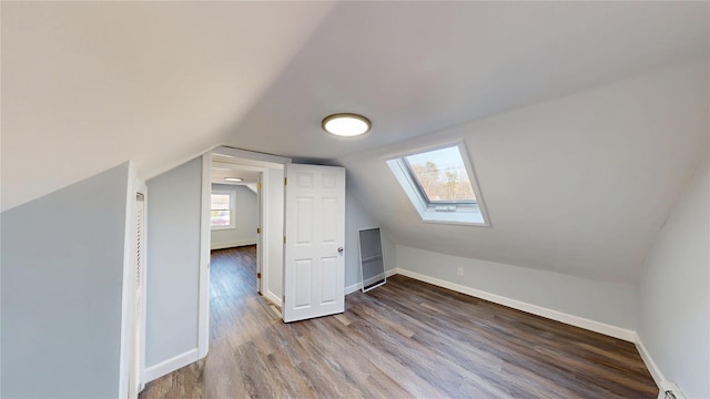 bonus room with lofted ceiling with skylight, a baseboard radiator, baseboards, and wood finished floors