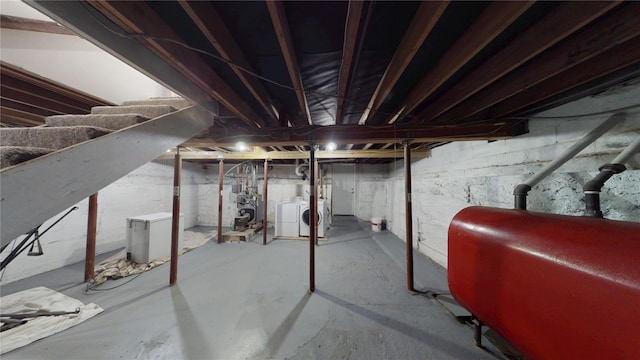 unfinished basement featuring washer and dryer, a heating unit, heating fuel, and fridge