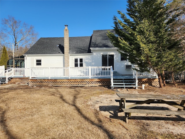 back of house with roof with shingles and a wooden deck