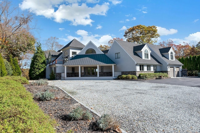 view of front of house featuring metal roof, stone siding, aphalt driveway, and a standing seam roof