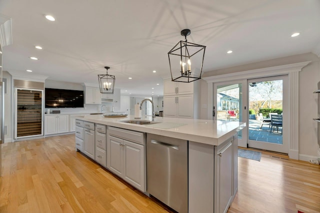 kitchen with a center island with sink, a sink, light countertops, white cabinets, and stainless steel dishwasher