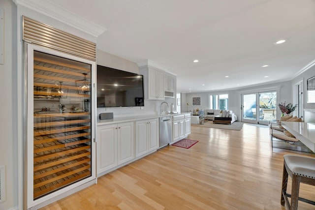 bar with light wood-style flooring, a sink, wine cooler, dishwasher, and crown molding