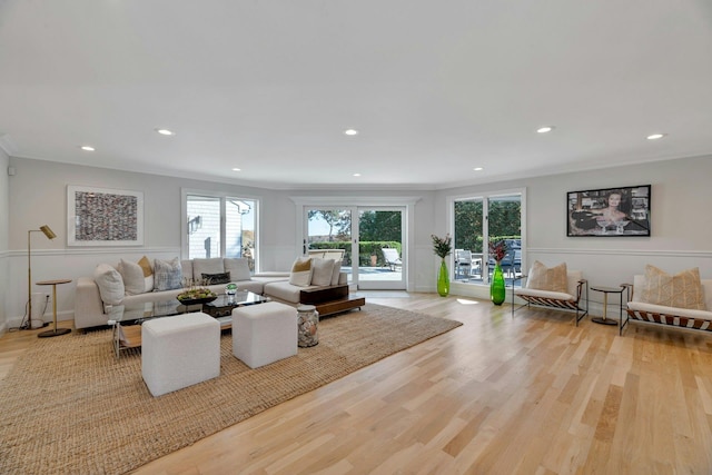 living room featuring crown molding, wood finished floors, and a healthy amount of sunlight