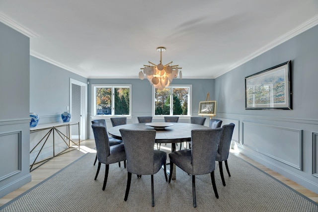 dining space featuring a decorative wall, light wood-type flooring, and crown molding