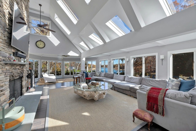 living area featuring a stone fireplace, a skylight, and ceiling fan