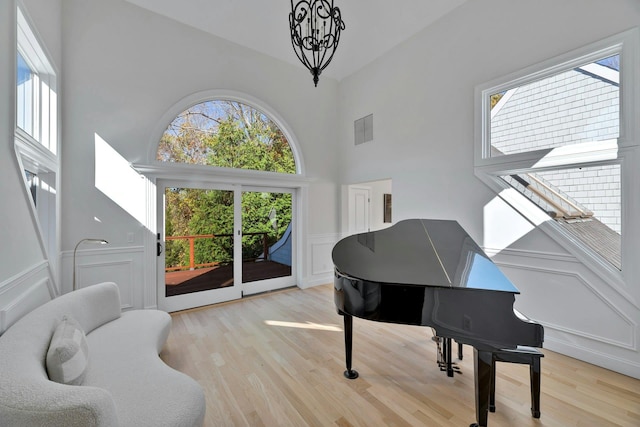 living area featuring visible vents, a high ceiling, a decorative wall, and light wood-style floors