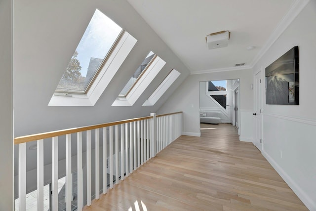 corridor with crown molding, vaulted ceiling with skylight, wood finished floors, and visible vents