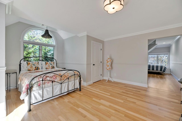 bedroom featuring vaulted ceiling, crown molding, baseboards, and wood finished floors