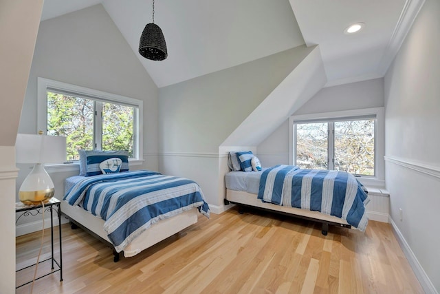 bedroom with vaulted ceiling, baseboards, and wood finished floors