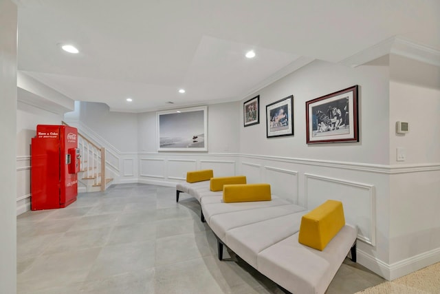 sitting room with recessed lighting, ornamental molding, stairs, and a decorative wall