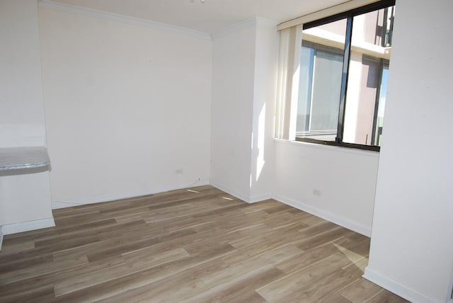 empty room featuring ornamental molding, wood finished floors, and baseboards