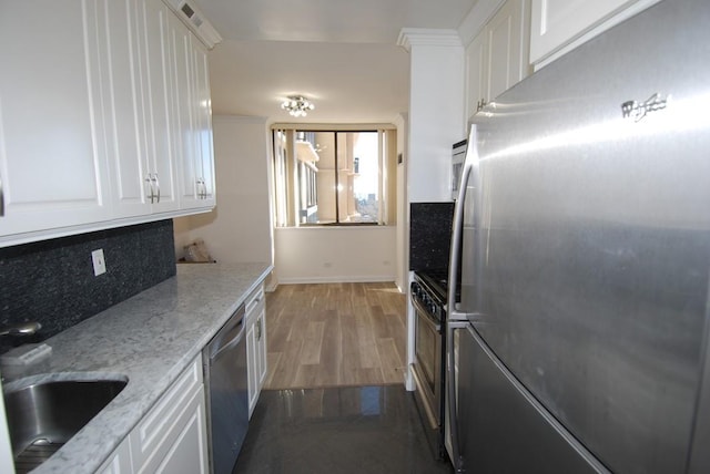 kitchen with dark wood-style floors, stainless steel appliances, tasteful backsplash, white cabinets, and a sink