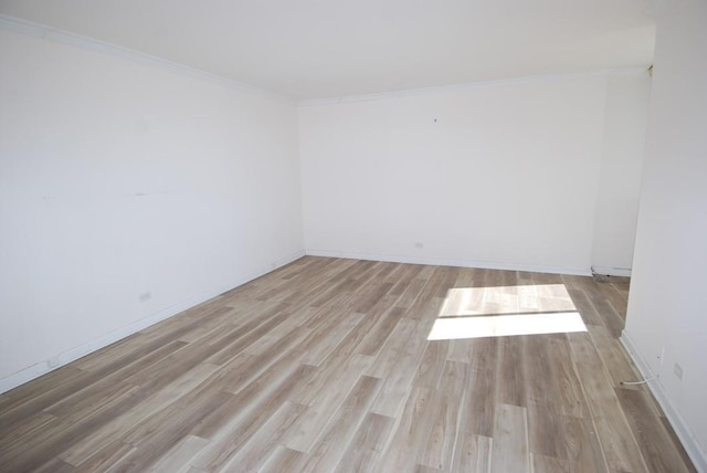 unfurnished room with baseboards, wood finished floors, and crown molding