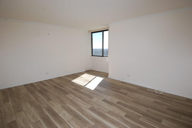 spare room with crown molding, baseboards, and wood finished floors