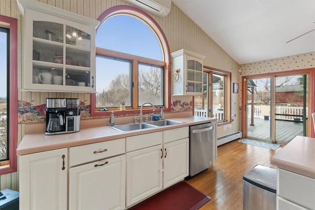 kitchen with a sink, vaulted ceiling, baseboard heating, dishwasher, and wallpapered walls