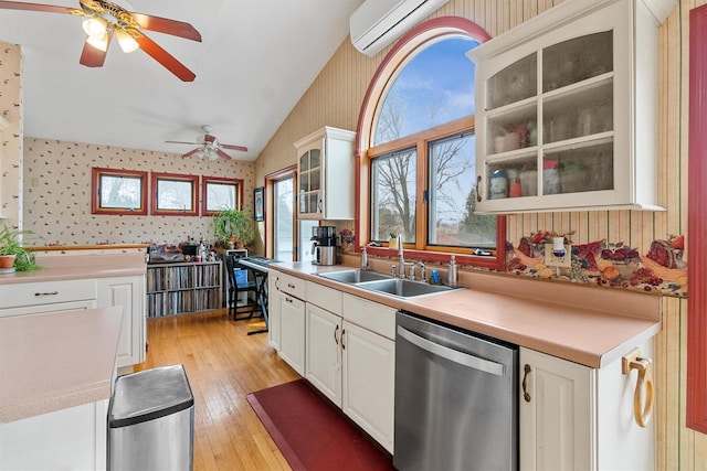 kitchen featuring dishwasher, a sink, lofted ceiling, and wallpapered walls