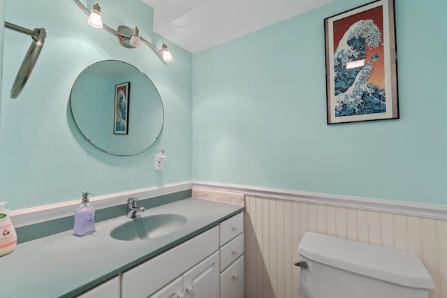 half bathroom featuring toilet, wainscoting, and vanity