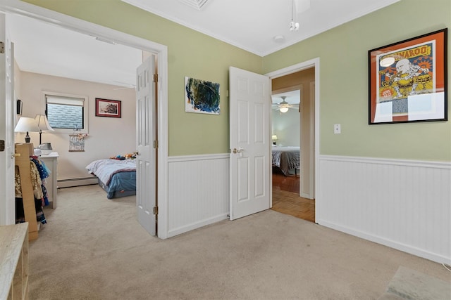 carpeted bedroom with a baseboard heating unit, a wainscoted wall, and ornamental molding