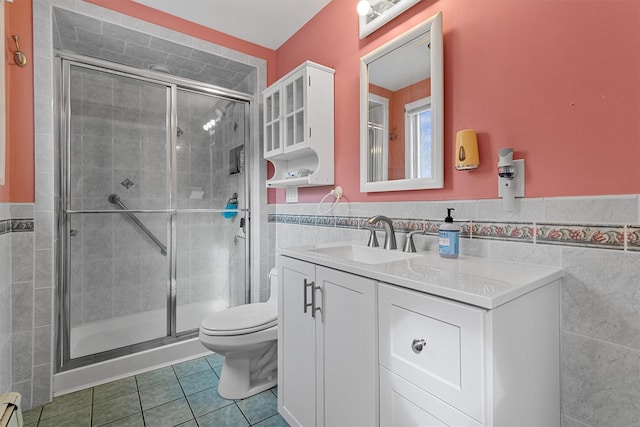 bathroom featuring toilet, vanity, tile walls, a shower stall, and tile patterned floors