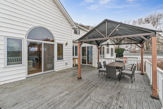 wooden terrace featuring outdoor dining area and a gazebo