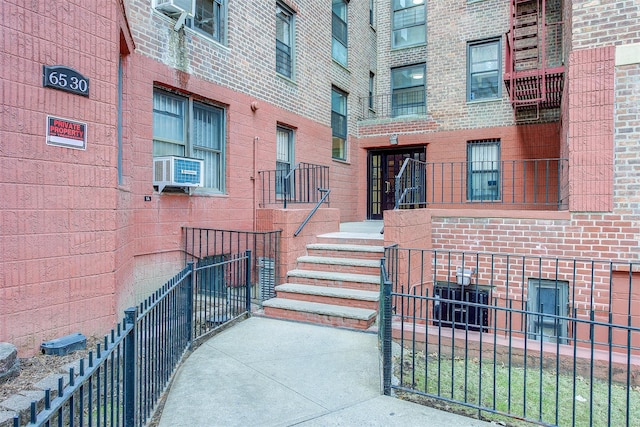 view of exterior entry featuring brick siding and cooling unit