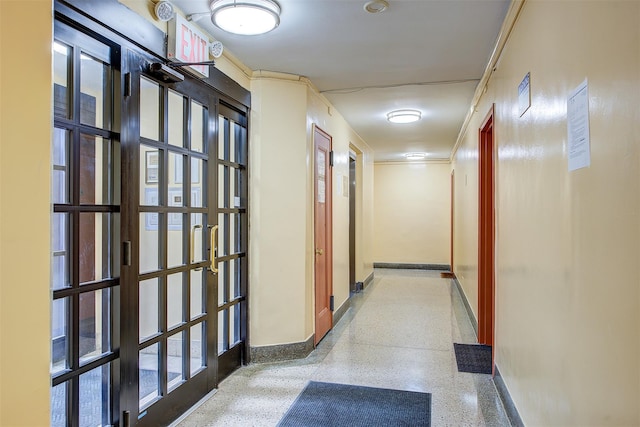 hallway with baseboards and speckled floor