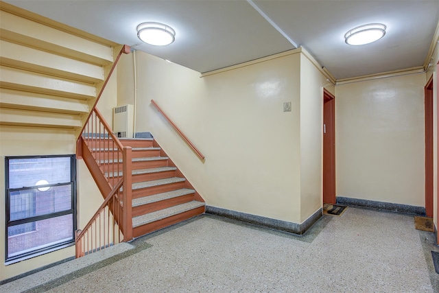 stairway featuring baseboards, ornamental molding, and speckled floor