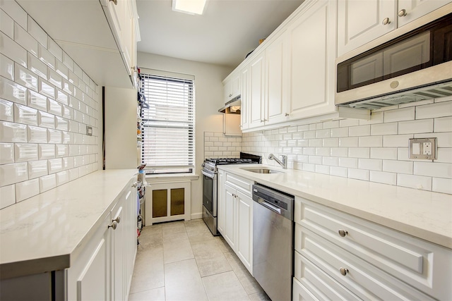 kitchen featuring appliances with stainless steel finishes, tasteful backsplash, a sink, and light tile patterned floors