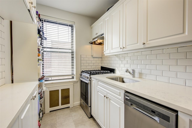 kitchen with tasteful backsplash, appliances with stainless steel finishes, white cabinets, a sink, and under cabinet range hood