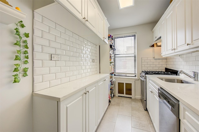 kitchen featuring light tile patterned flooring, stainless steel appliances, a sink, white cabinetry, and backsplash