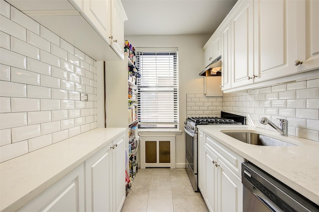 kitchen featuring decorative backsplash, appliances with stainless steel finishes, white cabinetry, a sink, and light tile patterned flooring